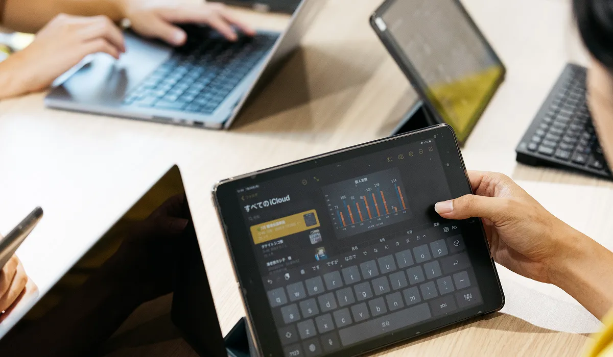 複数のデバイスが並ぶモダンなワークスペース、集中してデータ分析中のクローズアップ。