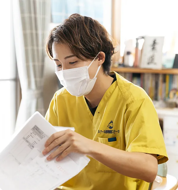 黄色いユニフォームのスタッフが真剣な面持ちで事務作業に取り組む。