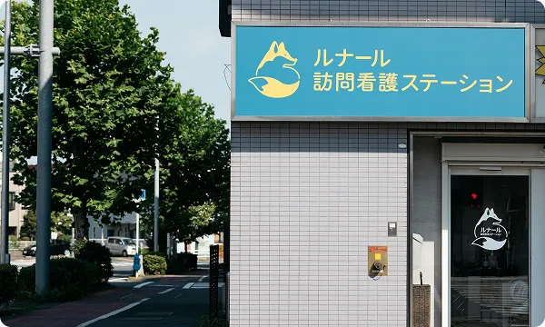 訪問看護ステーションの外観と看板が掲示された建物