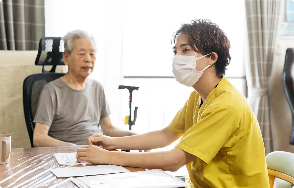 マスク越しに真剣な表情で話す介護職員と高齢者。