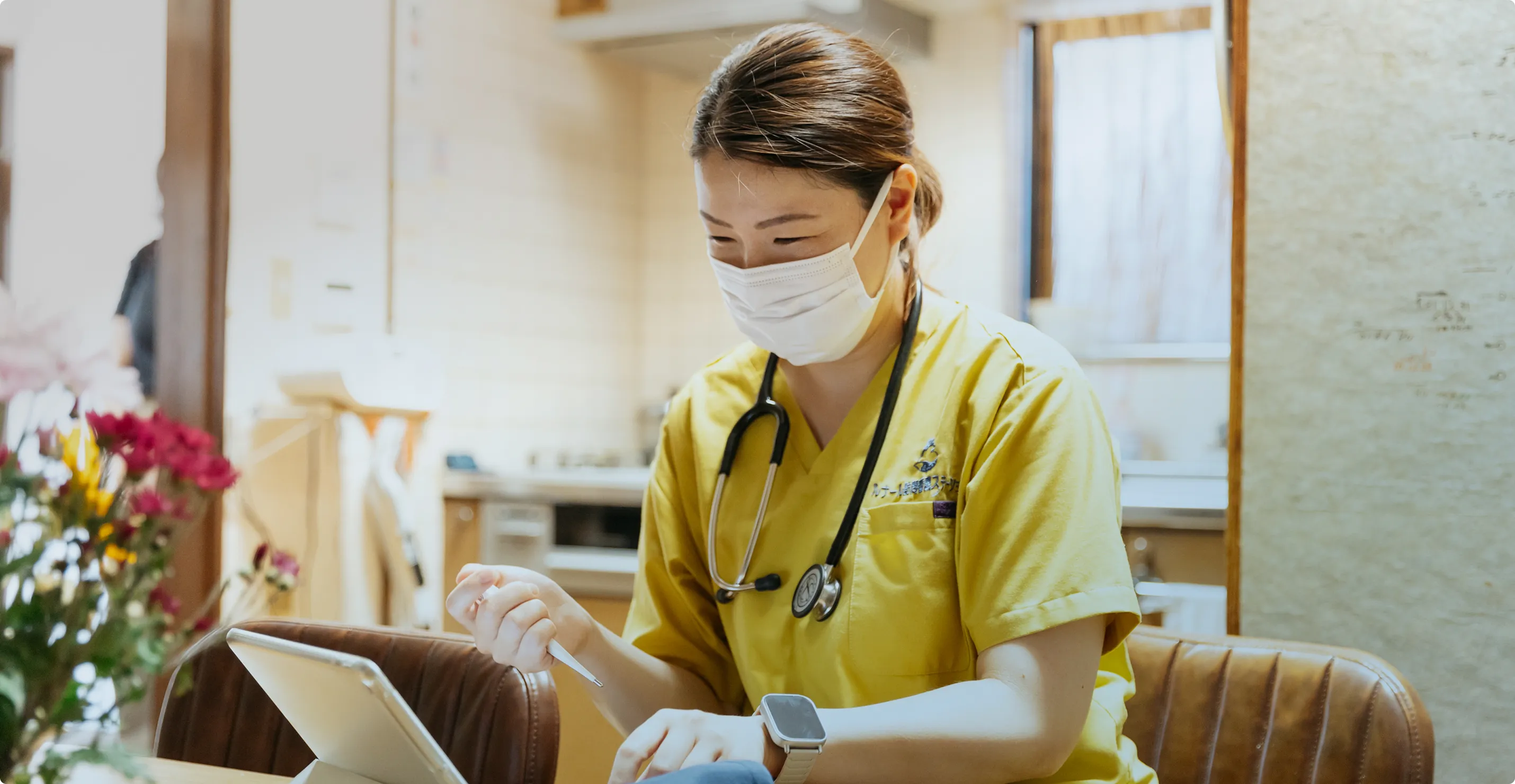 デジタルヘルスケア：集中してタブレットを操作するマスク姿の専門家。