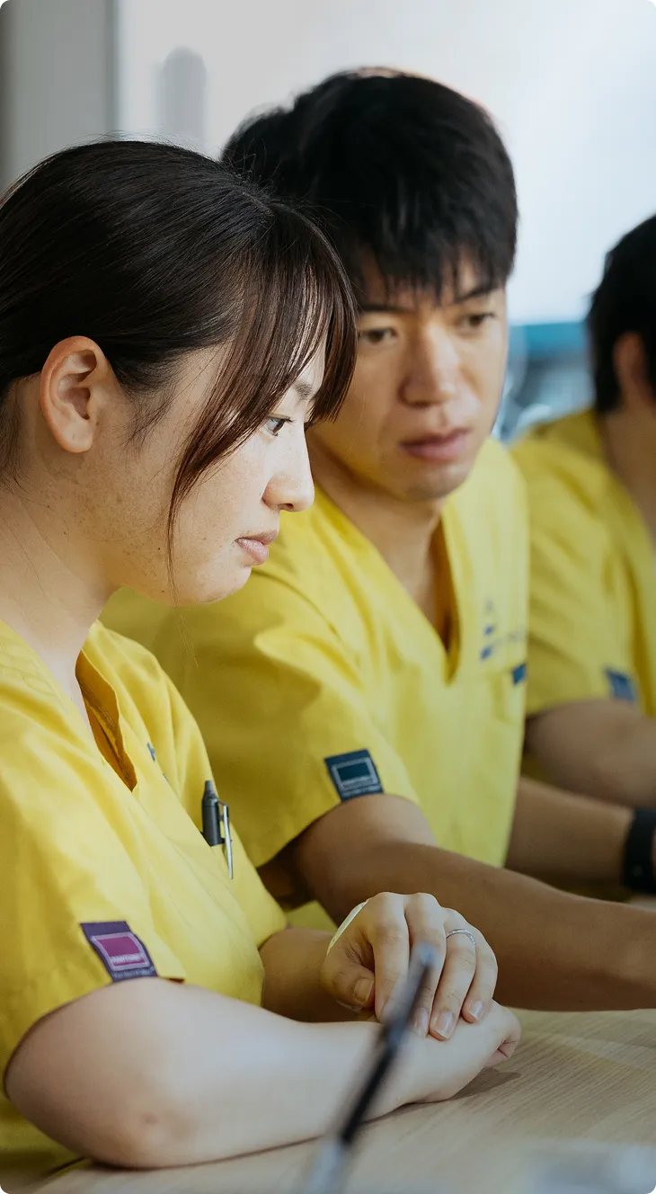 集中した表情でタブレットを操作する若者たち、チームでの知識共有の瞬間。